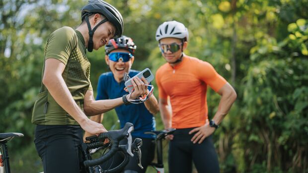 Asian Chinese male Professional cyclist resting in rural scene, showing smartphone mobile app GPS coordinates to his team . Travel, sport and modern technology concept.