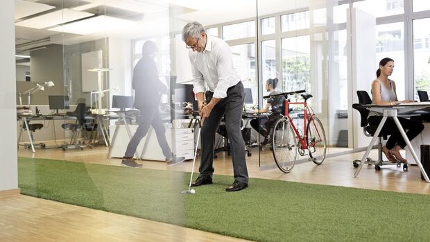 Businessman playing golf in office