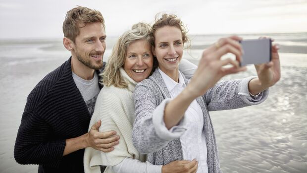 Couple and senior woman taking selfie on the beach