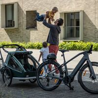 Croozer Fahrradanhäger für Kindertransport. Vater spielt mit Kindern, Fahrräder im Vordergrund