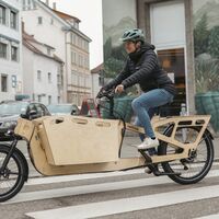 Frau fährt auf RETHINK E-Lastenrad aus Holz