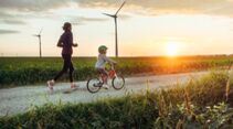 Kind auf Fahrrad, Mutter läuft im Sonnenuntergang