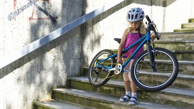 Kind trägt Fahrrad Treppe hinunter