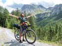 Man bikepacking, he stops and embraces nature arms wide open