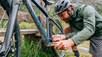 Man fixing mountain bike on trail