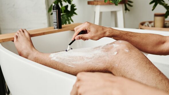 Man shaving his leg in bathroom