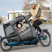 Mann mit 2 Kindern im Kindersitz auf der Front des Kettler Cargobikes
