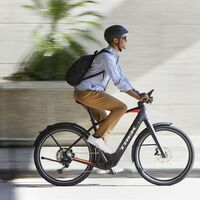 Mann mit Rucksack in der Stadt auf einem E-Bike Trek Allant+