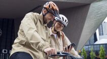 Mann und Frau mit Fahrrad tragen Abus Fahrradhelm