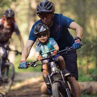 Mountainbiker mit kleinem Kind im Fahrrad-Kindersitz