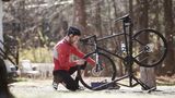 Side view of athlete adjusting bicycle on road during sunny day