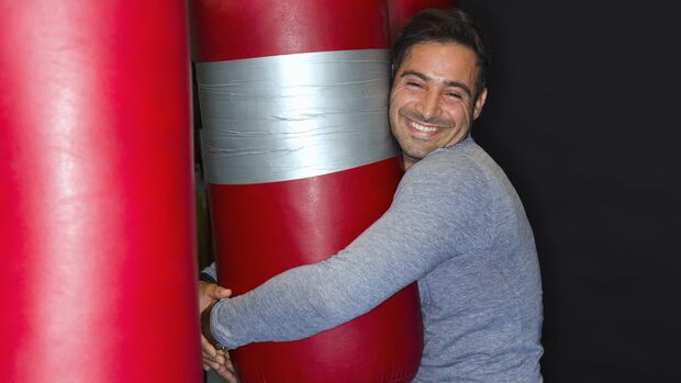 Smiling boxer hugging punching bag