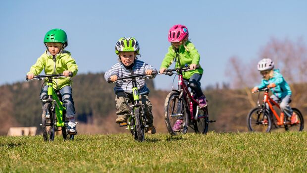 Vier Kinder fahren auf einer Wiese Fahrrad